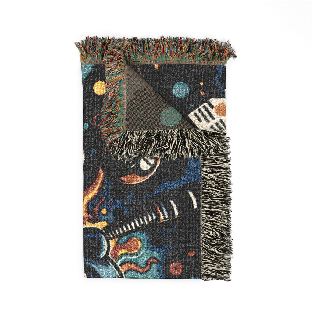 Folded woven blanket showing fringe and colorful artwork.