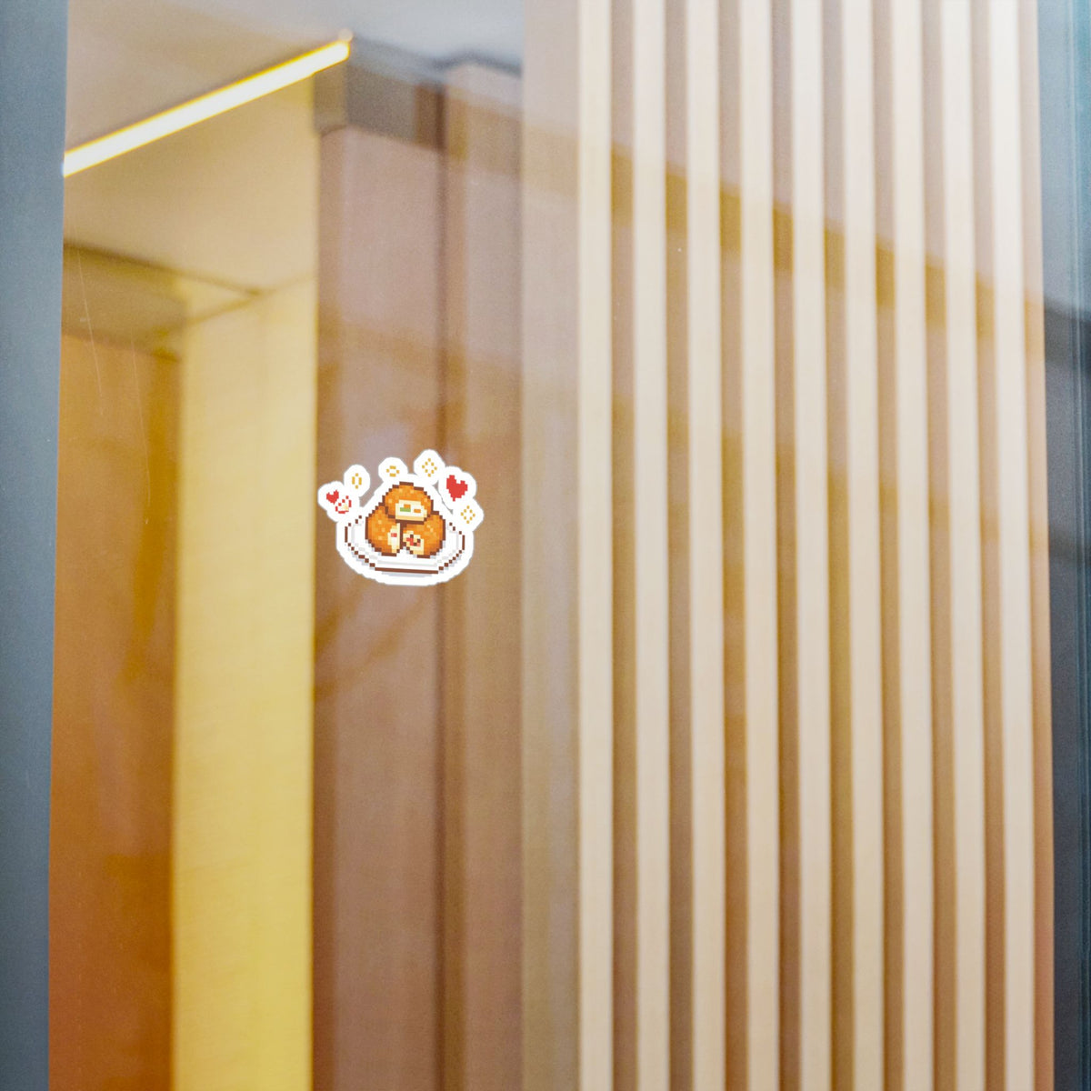 Sloth and apple-fritter sticker displayed on a glass panel.