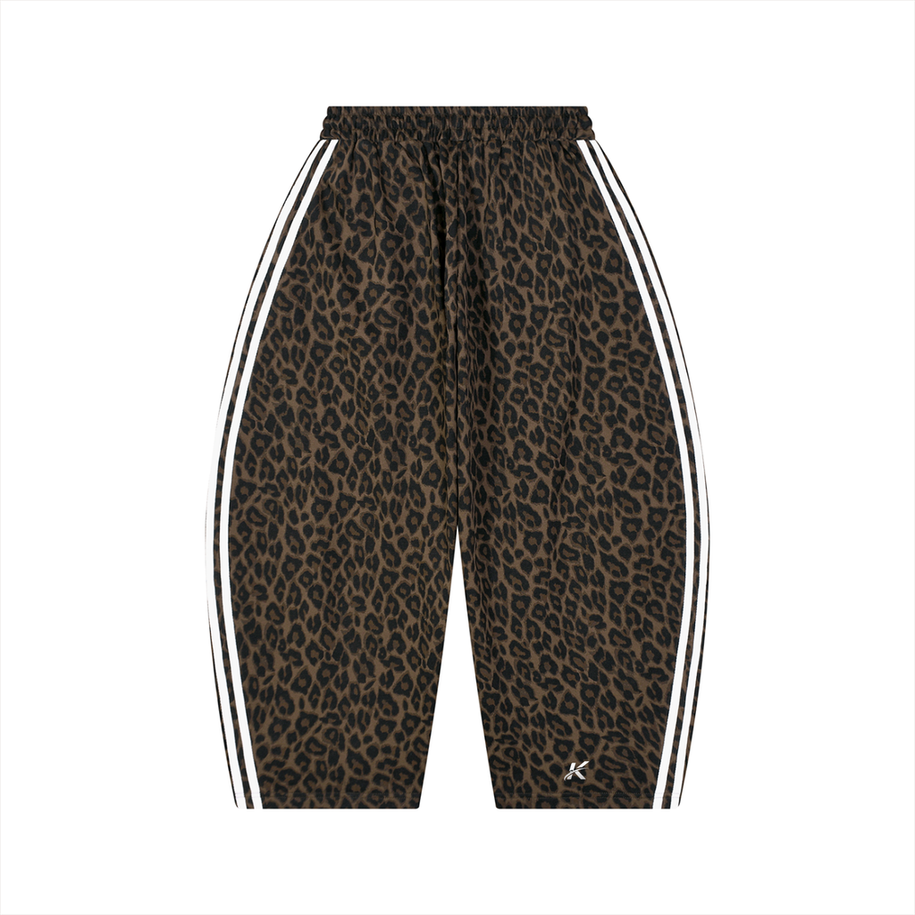 A pair of cropped athletic shorts featuring a brown and black leopard print pattern, with white double stripes running down the sides and a small white 'K' logo near the lower hem, shown against a plain white background.